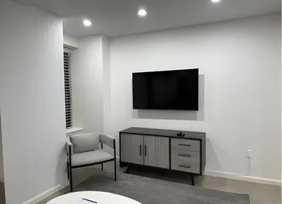 a living room with a tv and a chair at PlanURstay - Spacious Midtown West Fully-Serviced - 1BR & 1BTH in New York