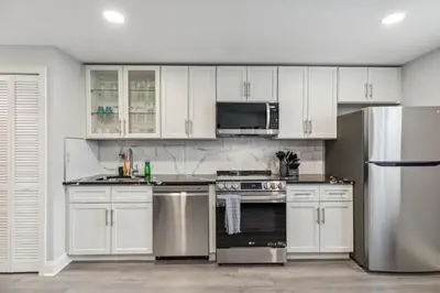 a kitchen with white cabinets and stainless steel appliances at AF Stays - Philadelphia Callowhill in Philadelphia