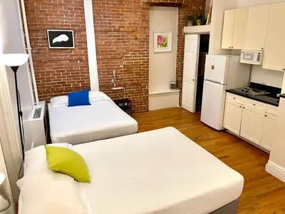 a small room with two beds and a brick wall at Nest Family Aparthotel - No Window in New York