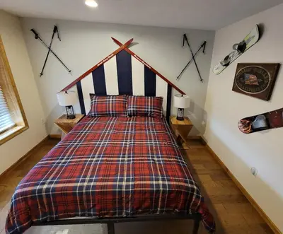 a bedroom with a bed with a checkered blanket at Swept Away Chalet - Luxurious NEW 6 BR Home Sleeps 16 Hot Tub Linens and Towels in Albrightsville