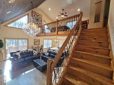 a living room with a staircase and a couch at Swept Away Chalet - Luxurious NEW 6 BR Home Sleeps 16 Hot Tub Linens and Towels in Albrightsville
