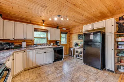 a kitchen with white cabinets and a black refrigerator at Game Room, Hot Tub! Cabin 9 Mi to Big Boulder Mtn in Albrightsville