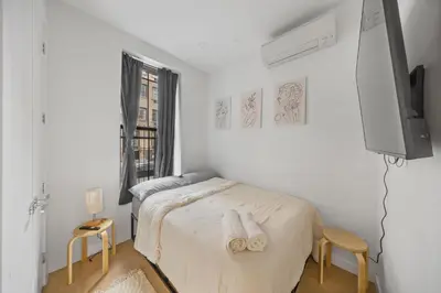 a white bedroom with a bed and a tv at Private Room with Shared Bathroom at an Apartment by Times Square in New York
