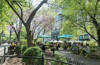 a group of people sitting at tables in a park at Steps from Everything - Modern 1-Bdr in Downtown's Union Square in New York