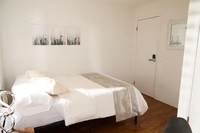 a white bedroom with a bed with white sheets at American Dream Guest House in New York