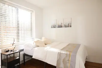 a white bedroom with a bed and a window at American Dream Guest House in New York