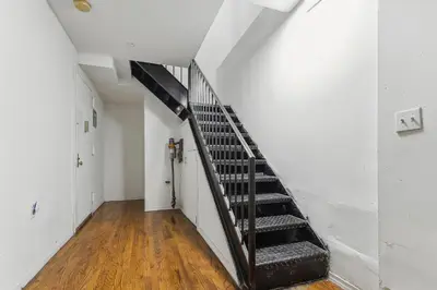 a staircase in a room with white walls and wooden floors at American Dream Guest House in New York