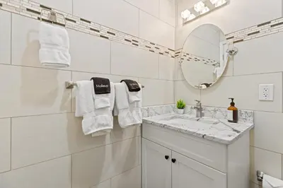 a white bathroom with a sink and a mirror at Elegant Urban Retreat in the Heart of Center City in Philadelphia