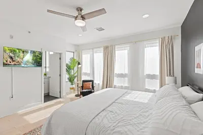 a white bedroom with a bed and a ceiling fan at Elegant Urban Retreat in the Heart of Center City in Philadelphia