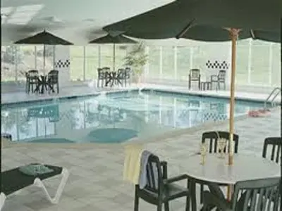 a pool with a table and chairs and an umbrella at Parkview Inn & Suites, Lancaster Amish Country, PA in Lancaster