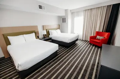 a hotel room with two beds and a red chair at Parkview Inn & Suites, Lancaster Amish Country, PA in Lancaster