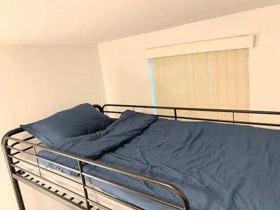 a bed with a blue blanket on it in a bedroom at Shered bathroom 4 SofaBed + loftbed + kitchen in New York