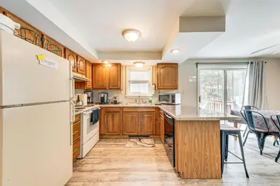 a kitchen with wooden cabinets and a white refrigerator at Arrowhead Lake Retreat with Private Indoor Pool! in Pocono Lake