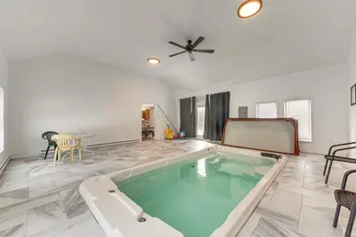 a swimming pool in a living room with a ceiling fan at Arrowhead Lake Retreat with Private Indoor Pool! in Pocono Lake