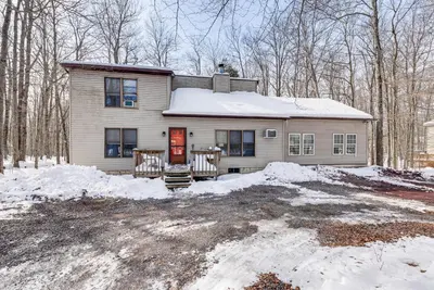 a house in the woods with snow on the ground at Arrowhead Lake Retreat with Private Indoor Pool! in Pocono Lake
