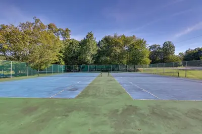 an empty tennis court with trees in the background at Game Room and Pool Access Pocono Paradise Haven in Tobyhanna
