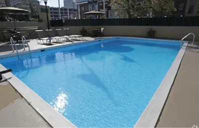 a large blue swimming pool with chairs and tables at PP 514 City Chic in a Modern Studio Haven in Harrisburg