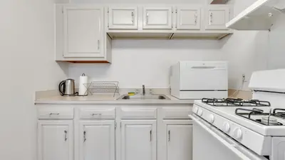 a white kitchen with a stove and a sink at PP 514 City Chic in a Modern Studio Haven in Harrisburg