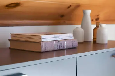 three books sitting on top of a counter with vases at Lakefront Log Cabin, Private Lake Access w/Peloton in Livingston Manor