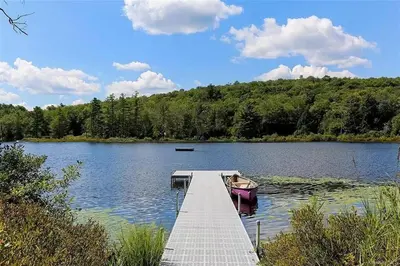 a boat is docked at a dock on a lake at Lakefront Log Cabin, Private Lake Access w/Peloton in Livingston Manor