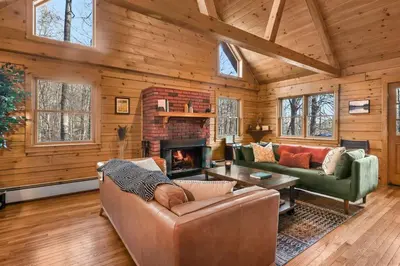 a living room with a couch and a fireplace at Lakefront Log Cabin, Private Lake Access w/Peloton in Livingston Manor