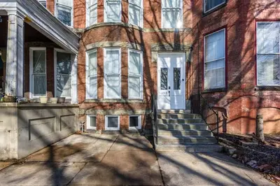 an old brick house with a white door and stairs at Flats on Front - Riverfront Gem Fast Wi-Fi 3F in Harrisburg