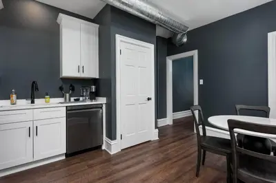 a kitchen with white cabinets and a table and a dining room at Flats on Front - Riverfront Gem Fast Wi-Fi 3F in Harrisburg