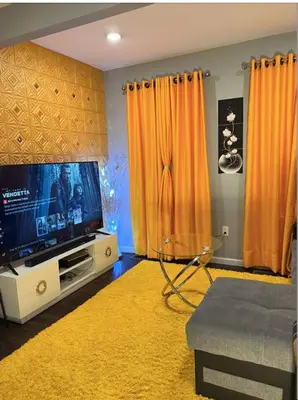 a living room with a television and orange curtains at Luxury Home in Linden