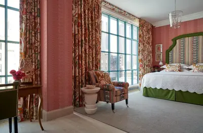 a bedroom with a bed and a chair and windows at Warren Street Hotel in New York