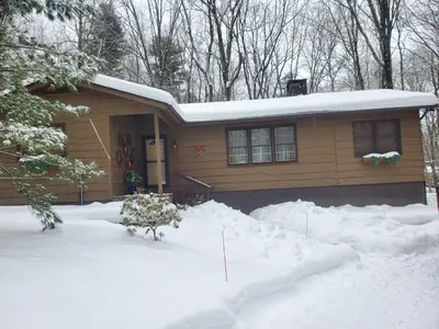 a house with a pile of snow in front of it at Harmony in the Woods in Lake Harmony