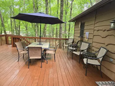 a deck with a table and chairs and an umbrella at Harmony in the Woods in Lake Harmony