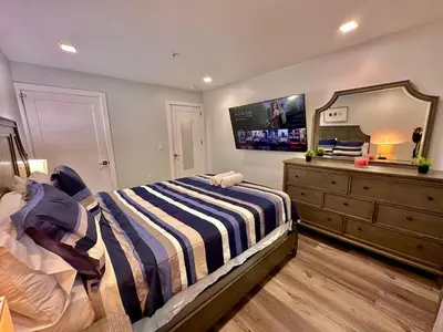 a bedroom with a bed and a dresser with a mirror at The Modern Suite - 2BR Close to NYC in Paterson
