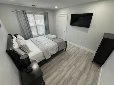 a bedroom with a bed and a flat screen tv at The Elegant Suite - 2BR with Great Amenities in Paterson