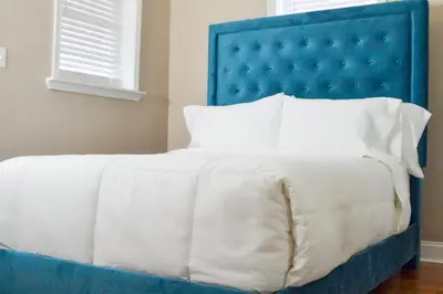 a bed with a blue headboard and white pillows at Beautiful Irving two bedroom apartment in Philadelphia