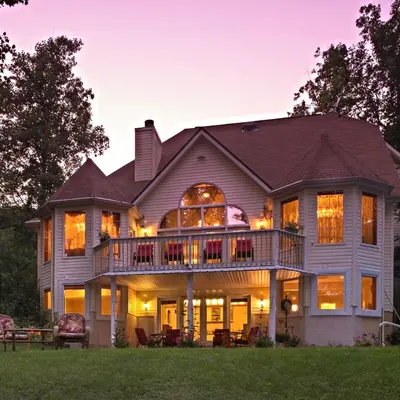 a large house with a wrap around deck at dusk at Cherry Valley Manor in Stroudsburg