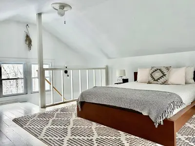 a bedroom with a bed and a white wall at renovatedhot tubnear skiingtubingcozy & chic in Monticello