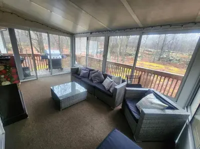 a living room with a couch and chairs and a balcony at Poconos Retreat in Bushkill