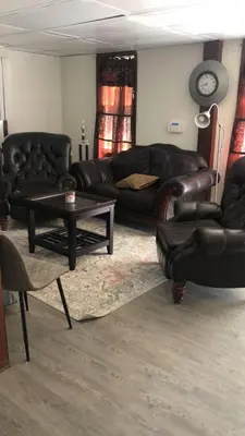 a living room with leather furniture and a table at room with a private shower in Arlington