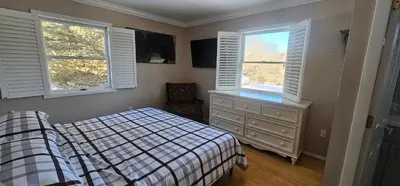 a bedroom with a bed and a dresser and two windows at Escape to the Catskills in Liberty