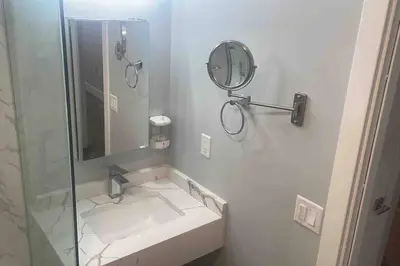a white bathroom with a sink and a mirror at The Comfy Suite - 1BR with Free Parking in Paterson