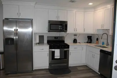 a kitchen with white cabinets and a stainless steel refrigerator at The Lovely Suite - 1BR close to NYC in Paterson