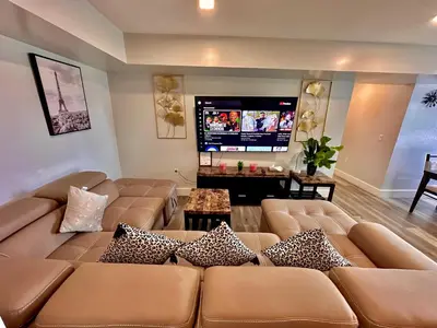 a living room with a large couch and a flat screen tv at The Classy Suite - 2BR with Free Parking in Paterson
