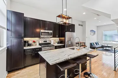 a kitchen with wooden cabinets and a large counter top at Roof Deck Oasis near PENN and CHOP in Philadelphia