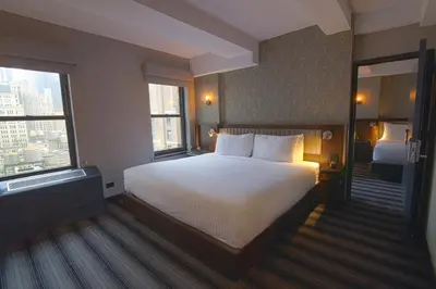 a hotel room with a bed and two windows at Hotel Edison Times Square in New York