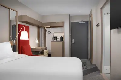 a bedroom with a white bed and a red chair at SpringHill Suites by Marriott New York Manhattan Times Square in New York