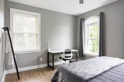 a bedroom with a bed and a desk and two windows at Pike Creek Palace 6 Bedrooms with 5 King beds Villa in Wilmington's Chateau Country in Wilmington