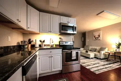 a kitchen with white cabinets and a living room at Redwood loft at Park Place King bed walk in closet fast WIFI and free coffee in Wilmington