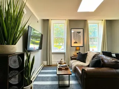 a living room with a leather couch and a table at The Grayson at Park Place- cozy and fully updated with King bed free coffee and fast WIFI in Wilmington