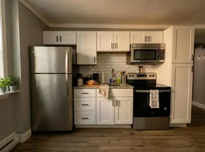 a kitchen with white cabinets and a stainless steel refrigerator at The Grayson at Park Place- cozy and fully updated with King bed free coffee and fast WIFI in Wilmington