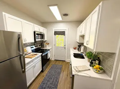 a kitchen with white cabinets and a stainless steel refrigerator at Cozy Walk up King Bed fast WiFi in Wilmington